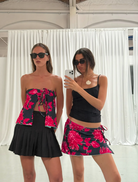 Two women in stylish black and pint skirts and tops capturing a selfie with smiles.