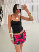  A woman wearing a floral dress poses for a selfie, capturing her cheerful expression against a natural backdrop.