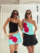 Two woman dressed in a skirt andtop takes a selfie, showcasing her outfit and bright smile.
