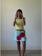A woman dressed in a skirt and Top, showcasing her outfit and bright smile.

