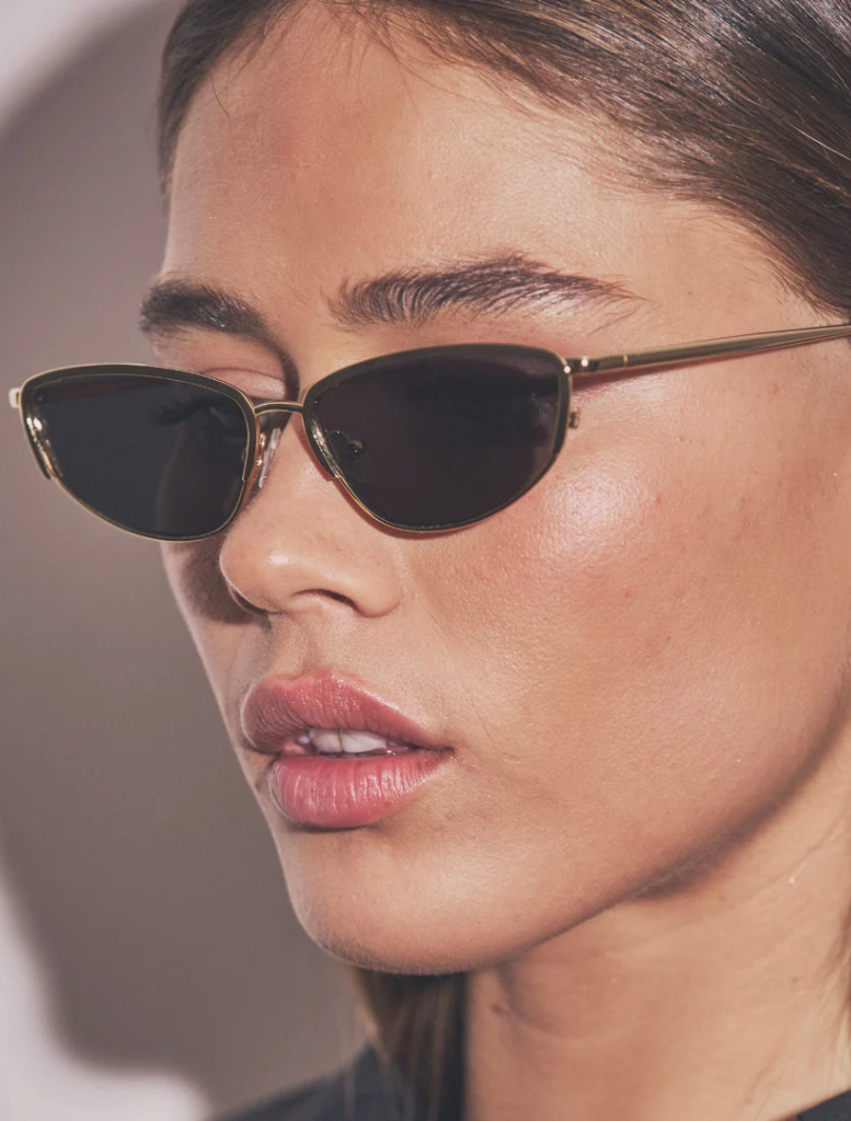 A close-up view of Santal tree bark, showcasing its unique texture and rich color against a blurred green background.