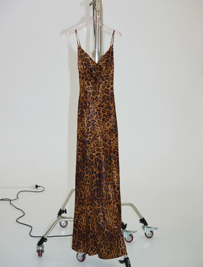 Stylish leopard print gown featuring a rosette detail, perfect for formal occasions and evening events.
