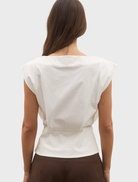 Simple ivory Shelly Top presented on a hanger, emphasizing its classic design for casual or formal occasions.