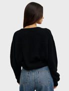 Black Sonia V-neck shirt laid flat, emphasizing its stylish cut and smooth fabric.