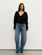 Black Sonia V-neck top displayed on a hanger, showcasing its elegant design and fabric texture.