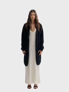 Black Sophia Open Cashmere Cardigan displayed on a hanger, showcasing its soft texture and elegant open-front design.