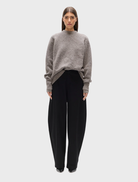 Beige grey Stella crew neck sweater displayed on a hanger against a neutral background.