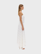 Milk-colored strapless dress with a sleek silhouette and a flowing skirt, ideal for warm weather occasions.