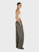 Stylish forest green Caleb pants displayed on a wooden backdrop, focusing on their elegant design and comfortable fit.