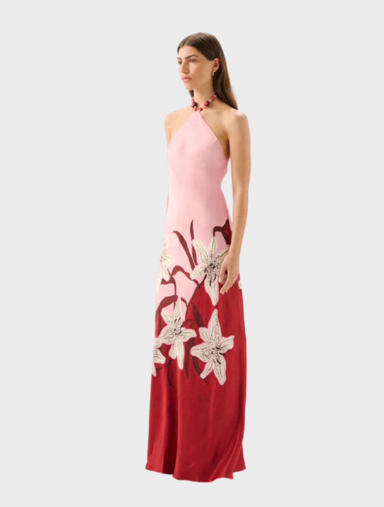 The Liliana Tallulah Halter Dress showcases a model in a vibrant pink and red floral dress.