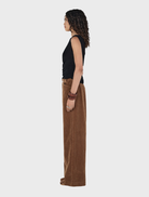 Tan Max Cord Pants displayed on a wooden surface, showcasing their soft texture and classic design.