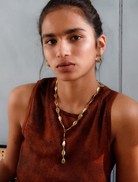 A long gold chain necklace adorned with a heart-shaped pendant, perfect for adding a touch of elegance.
