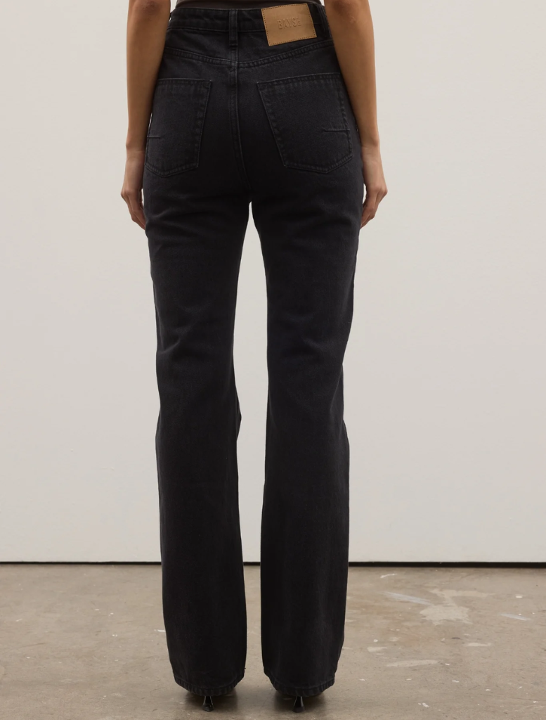 Backstage view of Tilly Bootleg Jean, highlighting its unique cut and fabric against a backdrop of fashion event preparations.