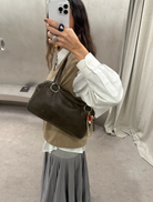 Brown leather handbag with two handles, highlighting its stylish and functional design.