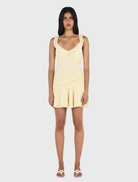 Fitted butter yellow mini dress with ruffles, deep V neckline, open back, and tiered flared skirt.