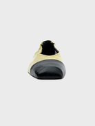  A yellow and black slip-on shoe made of pistachio oily crinkle leather, showcasing a stylish and modern design.