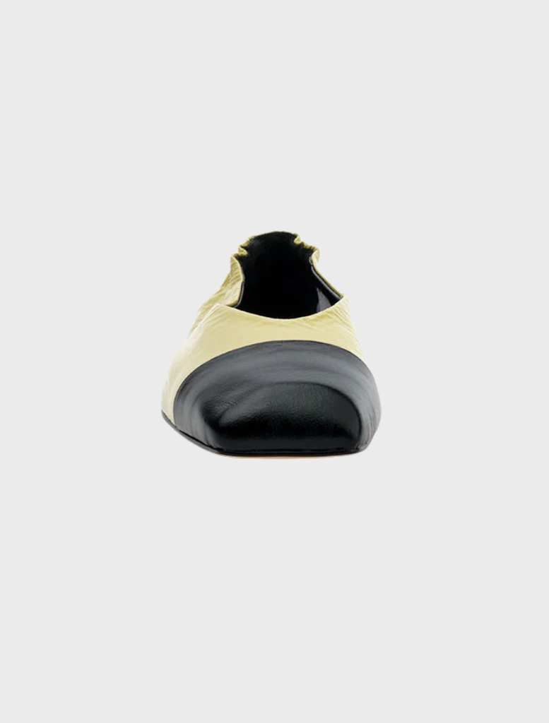  A yellow and black slip-on shoe made of pistachio oily crinkle leather, showcasing a stylish and modern design.