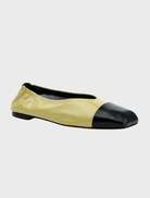 A pair of yellow and black flats featuring a black heel, made from pistachio oily crinkle leather.