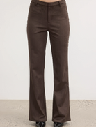  A model showcases a fashionable look, wearing brown pants and a coordinating top.