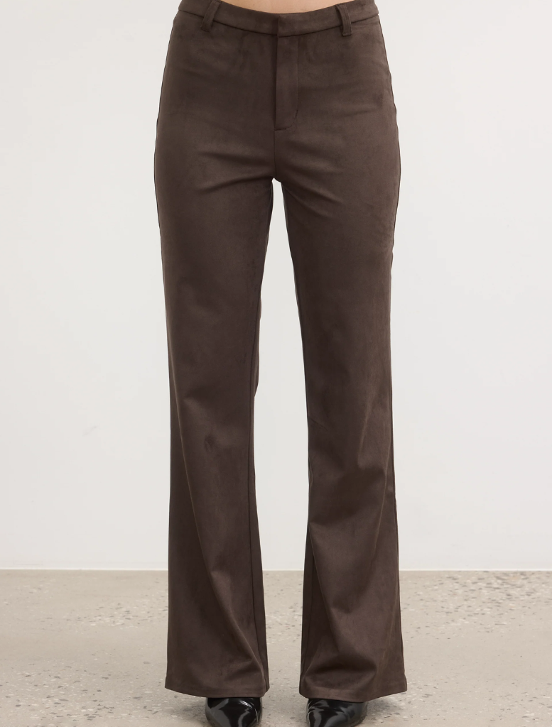  A model showcases a fashionable look, wearing brown pants and a coordinating top.