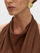 Brown Carrie dress draped on a chair, emphasizing its chic design with a comfortable fit and graceful lines.