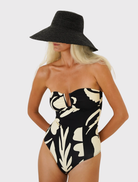 Sculpted bandeau swimsuit with a plunging neckline, spliced seams, and full back coverage in a warm cream and black print.