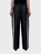 Modern black leather pants featuring a fitted design, suitable for both day and evening wear, combining comfort and style.