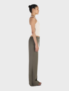 Caleb pants in a rich forest green color, positioned on a wooden surface, illustrating their contemporary design and fabric.