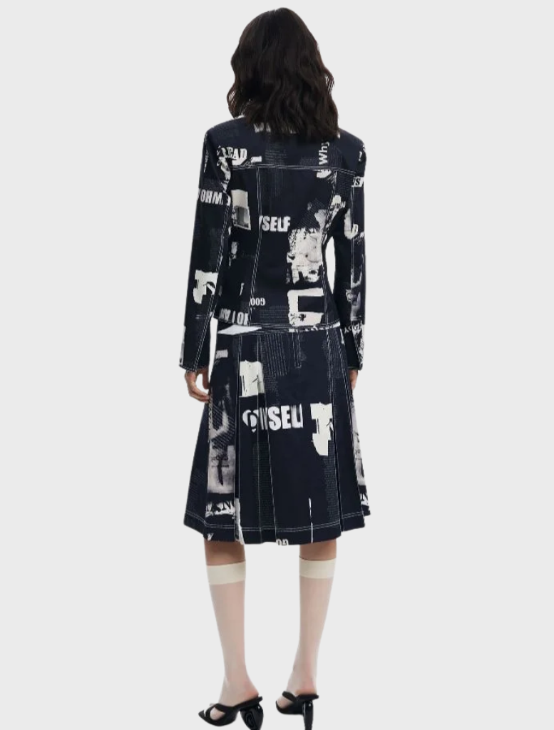 A model wears a black and white printed jacket and skirt, featuring the black Newspaper Pleated Midi Skirt.