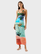  A woman models a bright dress adorned with colorful flowers, highlighting her cheerful style.