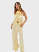 A model is dressed in pale yellow Celeste Jean Pants and a top, presenting a vibrant fashion look.