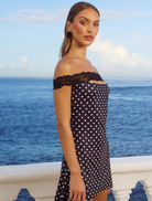 Chic black mini dress with white polka dots, featuring short sleeves and a sleek silhouette for versatile styling.