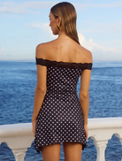 Black polka dot mini dress showcasing a fitted design and short sleeves, ideal for a trendy, casual outfit.